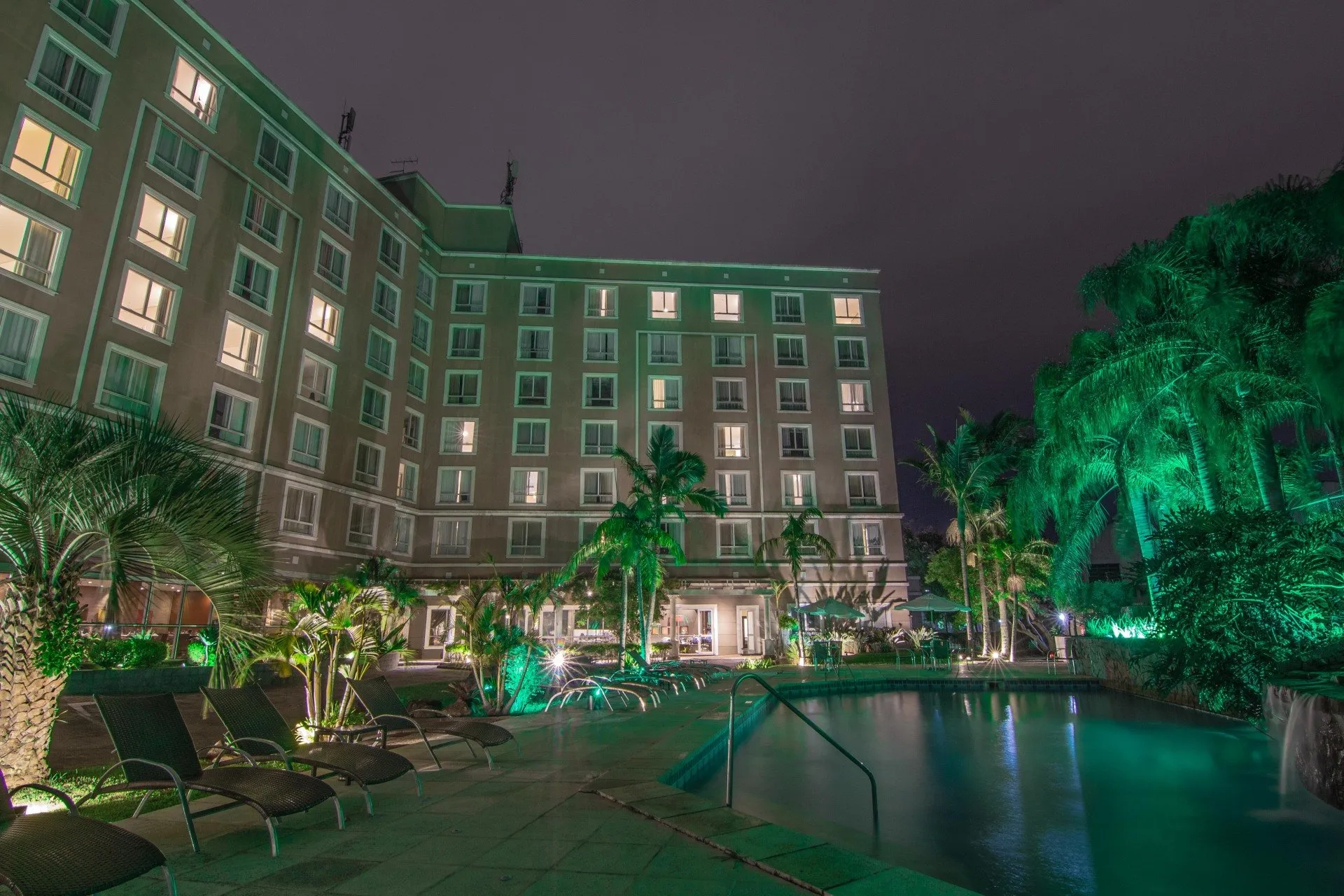 Hotel Deville Porto Alegre — fachada noturna com piscina e jardins